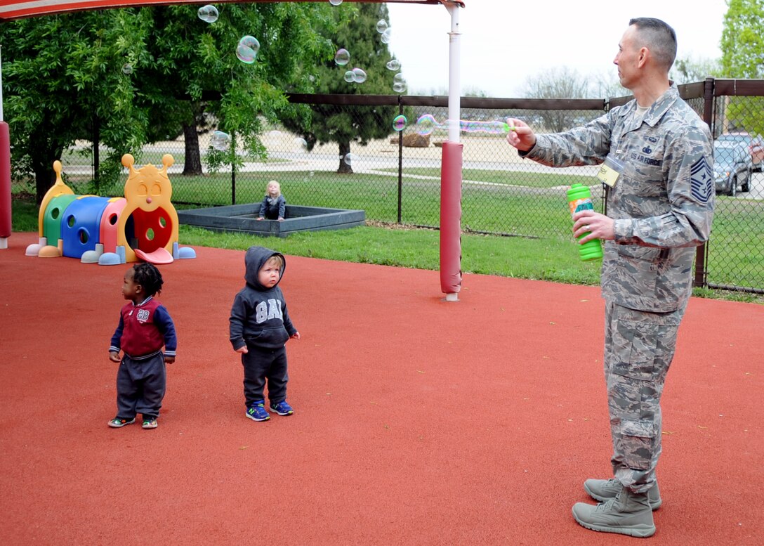 U.S. Air Force Chief Master Sgt. Todd Petzel, 18th Air Force command chief, blows bubbles for children at the Child Development Center, March 29, 2016, at Dyess Air Force Base, Texas. Petzel interacted with children while touring the CDC to learn what the program has to offer the Airmen and their families. (U.S. Air Force photo by Senior Airman Shannon Hall/Released)