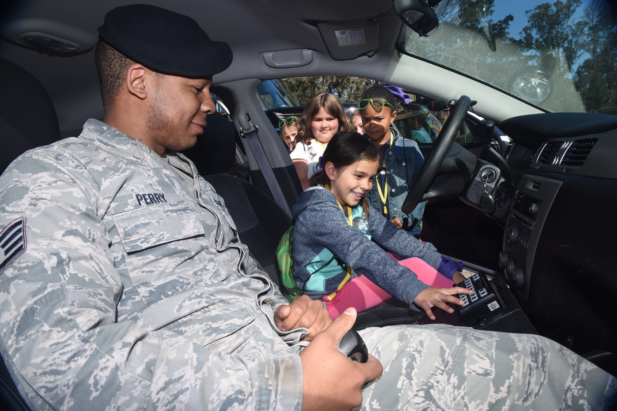 Staff Sgt. Benjamin Perry, 30th Security Forces patrolman, demonstrates patrol car capabilities during Kids Understanding Deployment Operations, March 29, 2016, Vandenberg Air Force Base, Calif. KUDOS is a program developed to give children a deeper understanding of the military deployment process and equipment utilized during a deployment. (U.S. Air Force photo by Staff Sgt. Jim Araos/Released)