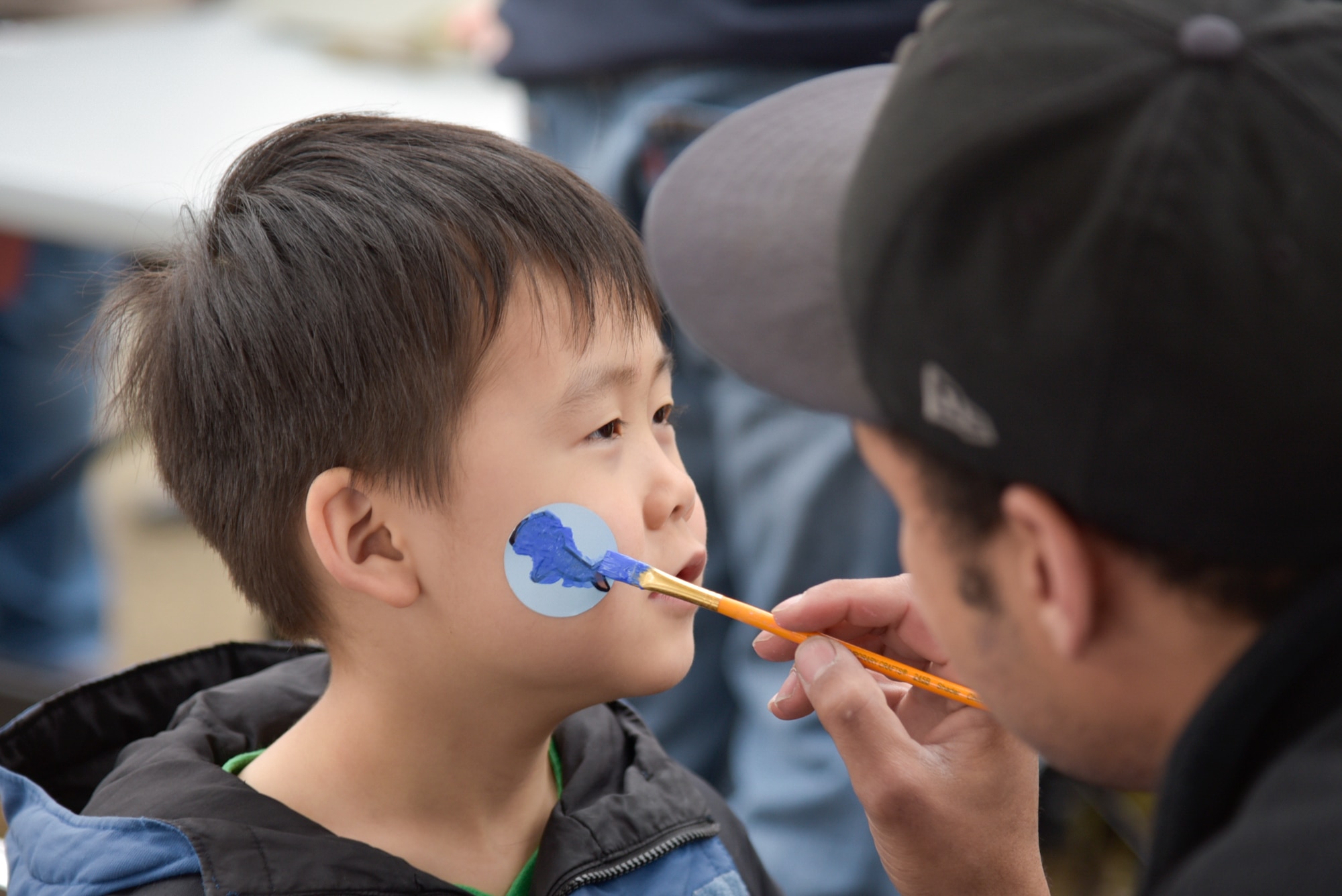 Mikee Mihaylov, 6, son of Senior Airman Nikolay Mihaylov, 374th Force Support Squadron fitness specialist, has his face painted during the Sakura Spring Festival at Yokota Air Base, Japan, April 2, 2016. Festivities of the day included bouncy castles, juggling, face painters and a balloon artist. (U.S. Air Force photo by Machiko Imai/Released)