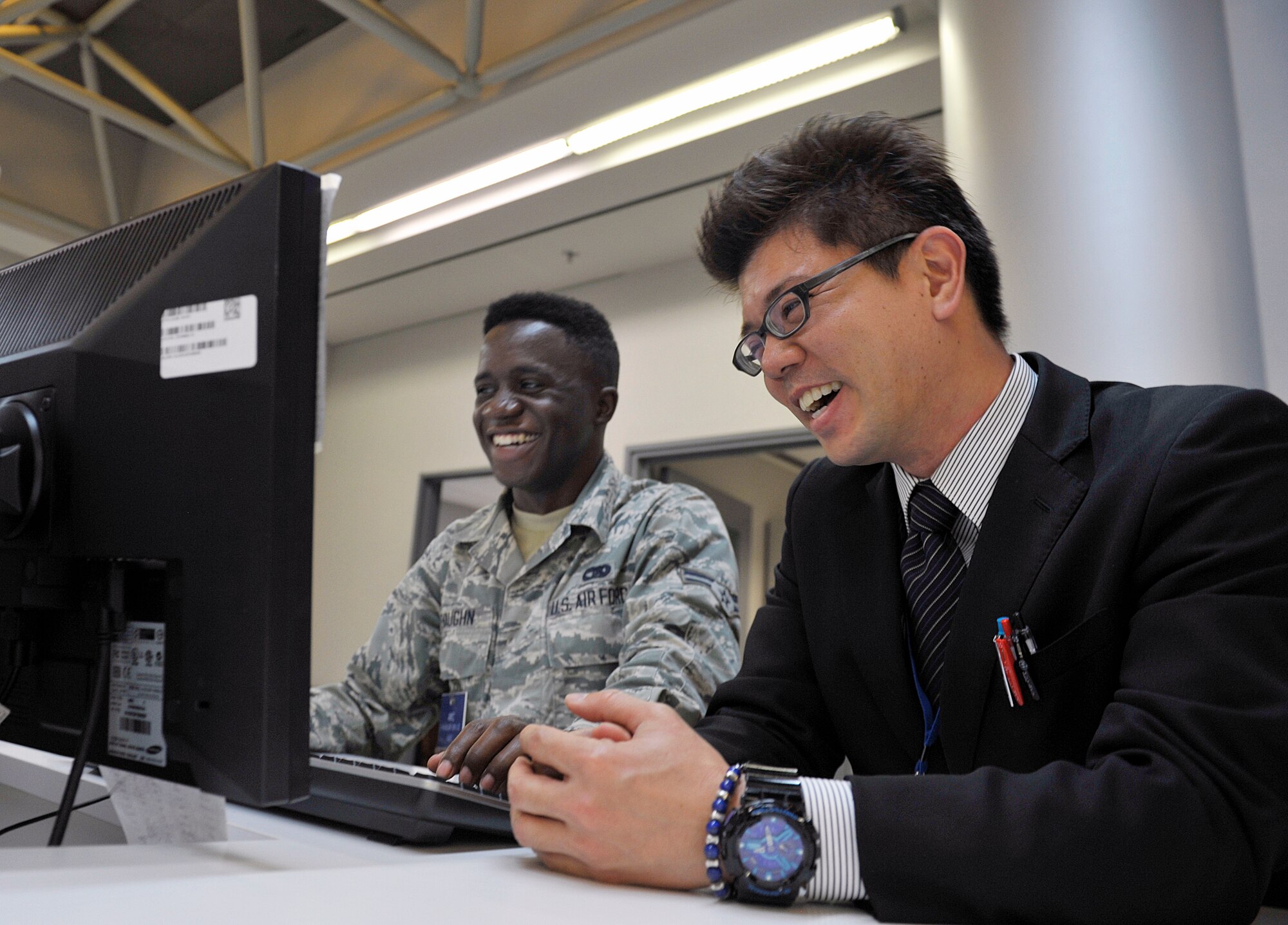 Tomokazu Arakaki, 733rd Air Mobility Squadron passenger service agent, interacts with a U.S. Air Force Airman 1st Class Earl Devaughn, 733rd AMS passenger service agent, at the 733rd AMS Passenger Terminal, April 1, 2016, at Kadena Air Base, Japan. According to Arakaki, members from the 733rd AMS Passenger Terminal treat him like family. (U.S. Air Force photo by Naoto Anazawa)

