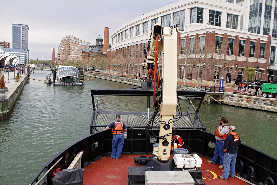 The crew on board the Reynolds, U.S. Army Corps of Engineers' steel debris vessel, approaches the Waterwheel Powered Trash Interceptor, also known as Mr. Trash Wheel, located in the Baltimore Inner Harbor on April 4, 2016. Col. Edward Chamberlayne, Commander, Baltimore District, visited with the team behind Mr. Trash Wheel to discuss similarities in their respective missions toward a cleaner Baltimore Harbor.