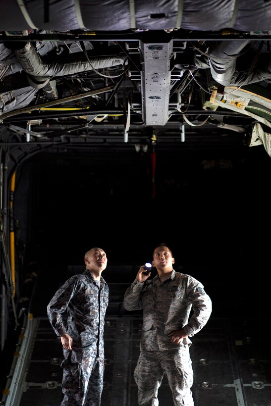 U.S. Air Force Staff Sgt. Gene Phonthipsavath, right, explains capabilities of C-130 Hercules equipment to Japanese Air Force Tech. Sgt. Masahiro Nakanishi, Special Airlift Group crew chief, at Yokota Air Base, Japan, March 23, 2016. Phonthipsavath is a crew chief assigned to the 374th Aircraft Maintenance Squadron and Nakanishi is a crew chief assigned to the Special Airlift Group. Air Force photo by Osakabe Yasuo