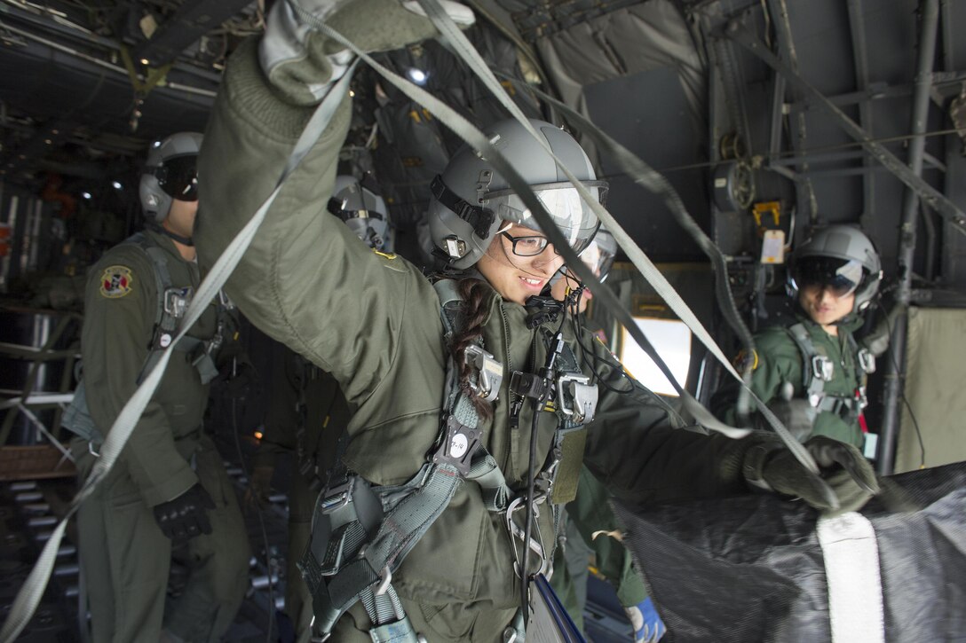 U.S. Air Force Airman 1st Class Marissa Antillon-Loya, foreground, tightens a strap after deploying a low-cost, low-altitude airdrop from a C-130 Hercules aircraft during an annual Non-Commission Officer exchange program over Yokota Air Base, Japan, March 23, 2016. Antillon-Loya is a loadmaster assigned to the 36th Airlift Squadron. Air Force photo by Osakabe Yasuo