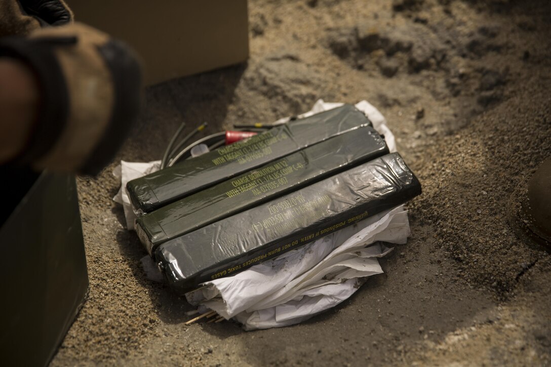 U.S. Marines with Explosive Ordinance Disposal Company, 8th Engineer Support Battalion lay blocks of M112 demolition charge on top of trinitrotoluene, commonly known as TNT, from a 155 mm artillery round during a clean-up shot at Camp Lejeune, N.C., April 1, 2016. Days prior to the clean-up shot, the Marines used the Thermally Controlled Explosive Removal System to safely remove the TNT charge from the 155mm artillery round. The shells will later be used as displays to aid in teaching students about the characteristics of the round. (U.S. Marine Corps photo by Cpl. Justin T. Updegraff/ Released)