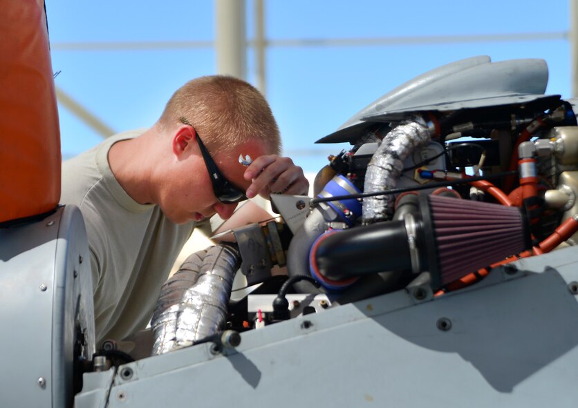 Senior Airman Jonathan, 432nd Aircraft Maintenance Squadron MQ-1 Predator crew chief, wipes his brow after adjusting the throttle on an MQ-1 Predator April 5, 2015 at Creech Air Force Base, Nevada. During a post-flight check, crew chiefs complete inspections to replace broken parts or replace parts that have met their flight time service life. (U.S. Air Force photo by Senior Airman Christian Clausen/Released)