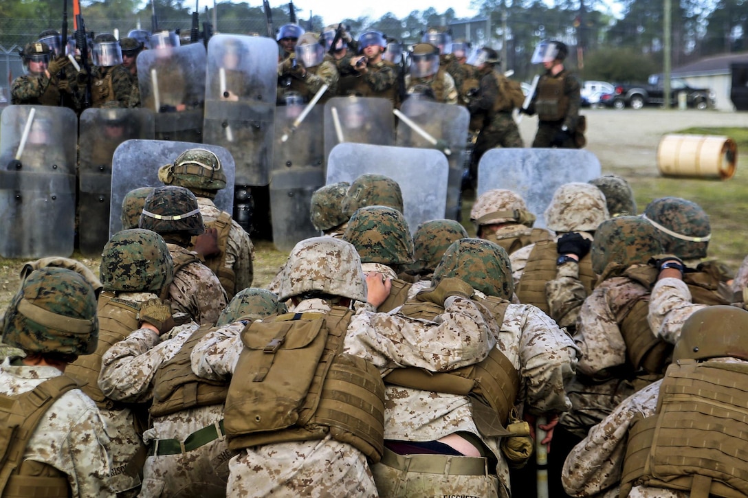 A group of Marines role-plays as rioters as a Marine Corps riot control unit conducts training on crowd-control methods at Marine Corps Base Camp Lejeune, N.C., March 25, 2016. The Marines are with Combat Logistics Battalion 2. Marine Corps photo by Cpl. Joey Mendez