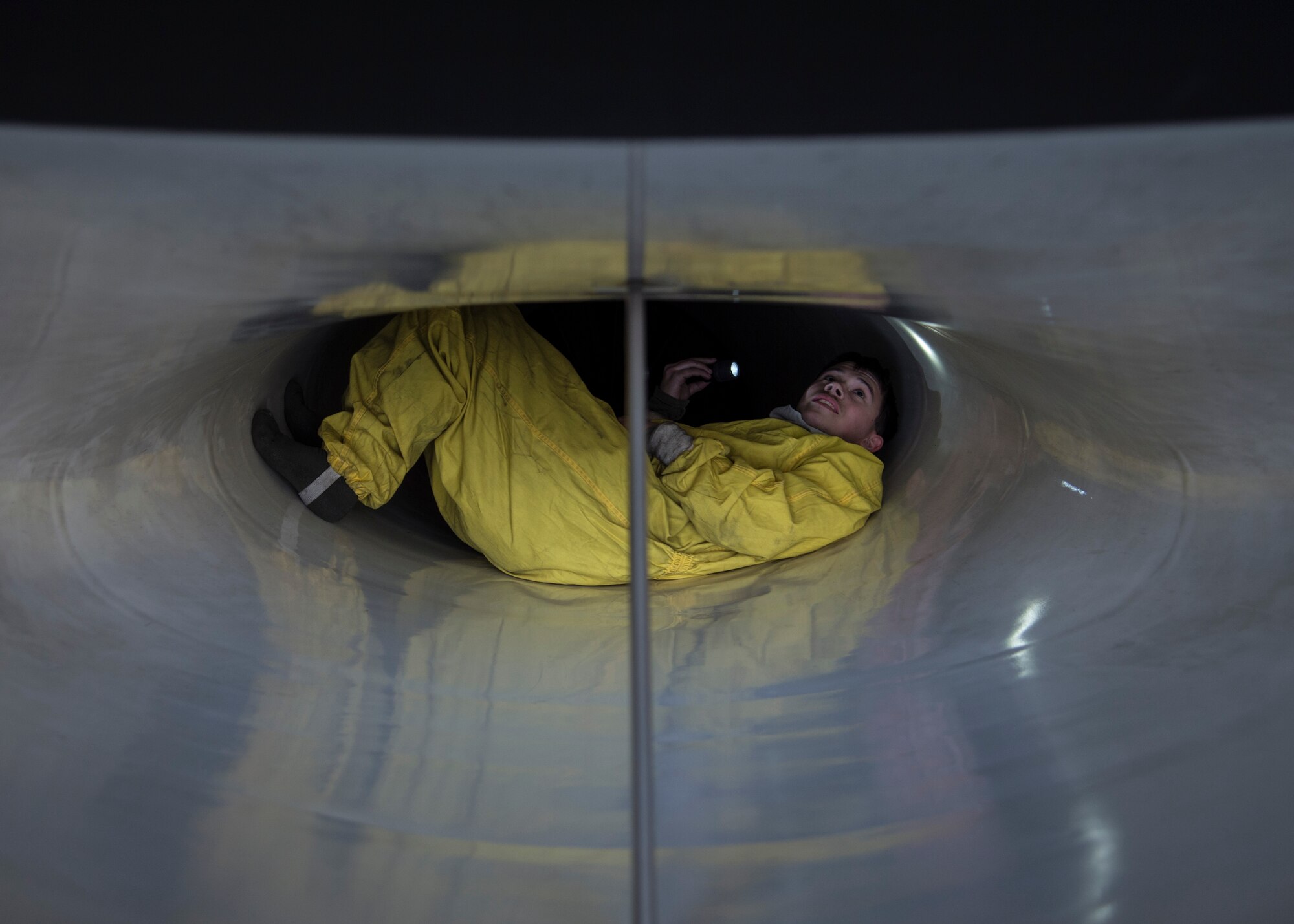 U.S. Air Force Senior Airman Bradley Poirier, a crew chief with the 35th Aircraft Maintenance Squadron, inspects the intake of an F-16 Fighting Falcon during a two-day surge exercise at Misawa Air Base, Japan, April 5, 2016. Aircraft intakes are checked for appearance of foreign object debris or damaged blades during post-flight inspections. Protective suits are worn to increase maneuverability and prevent damage to the intake. (U.S. Air Force photo/Airman 1st Class Jordyn Fetter/Released)