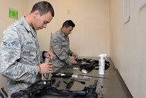 Airmen First Class Miguel Pichardo and Eduardo Granados, 2nd Security Forces Squadron installation entry controller, clean their weapons at Barksdale Air Force Base, La., April 1. Airmen assigned to 2nd SFS clean their M4 carbine and Beretta M9 monthly to keep them in proper working condition. (U.S. Air Force photo/Senior Airman Amanda Morris)