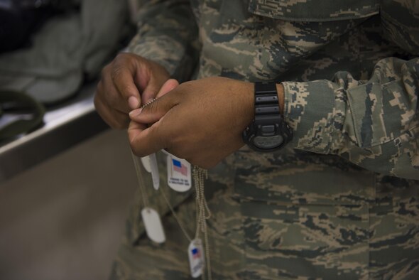 An Airman detangles mock dog tags for children attending the Gunfighter Jr. event April 4, 2016, at Mountain Home Air Force Base, Idaho. These dog tags were handed out to children participating in the event. (U.S. Air Force photo by Airman Alaysia Berry/Released)