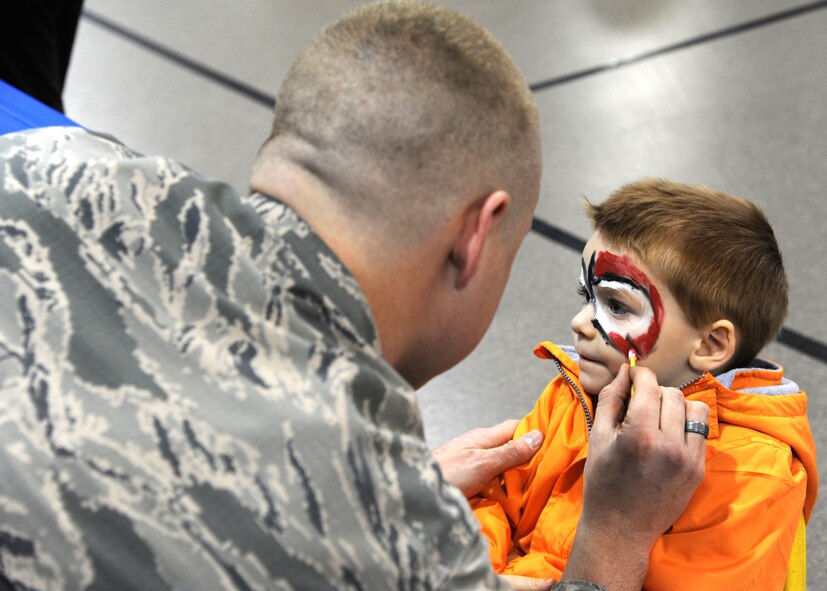 Senior Airman Brandon Henegar, 319th Medical Operations Squadron aerospace medical services technician journeyman, paints the face of Gabriel Henry, 4, at the Beautiful Child Photo Shoot and Activity Fair April 5, 2016, on Grand Forks Air Force Base, N.D. Henegar was one of many Airmen who volunteered at the event in support of the Month of the Military Child. (U.S. Air Force photo by Airman 1st Class Ryan Spark/Released)