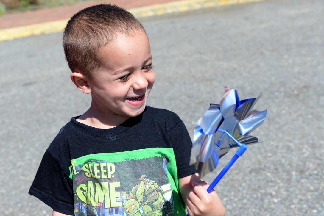 A child smiles after receiving a pinwheel during a National Child Abuse Prevention Month event at Langley Air Force Base, Va., April 1, 2016. The pinwheel is the national symbol for child abuse prevention and is planted each April to raise awareness for the cause. (U.S. Air Force photo by Airman 1st Class Kaylee Dubois)