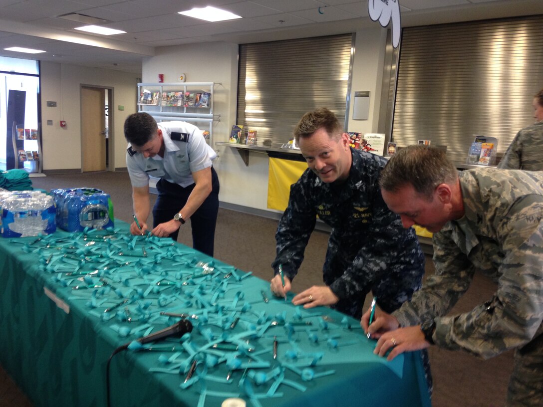 Sexual Assault Awareness Month is recognized every April to raise awareness about sexual violence and help educate the community on how to reduce the risk of it occurring. Col. Christopher Finerty, ANGRC Acting Commander, CAPT Scott Fuller, NAFW Commander and Col. Bradley Hoagland 11th Wing Commander signed teal ribbons at the Community Commons, on April 4, in a pledge of support to help end sexual violence by addressing inappropriate behavior and treating others with dignity and respect. (Photo by Andrea Verdino)