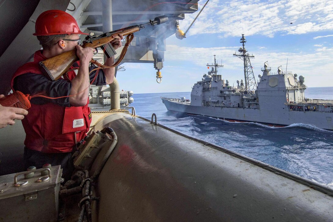 Navy Petty Officer 2nd Class Garrett Kio fires a shot line to the guided-missile cruiser USS San Jacinto from the aircraft carrier USS Dwight D. Eisenhower at sea, April 4, 2016. The Dwight D. Eisenhower is conducting training to prepare for a deployment. Navy photo by Petty Officer 3rd Class Anderson W. Branch
