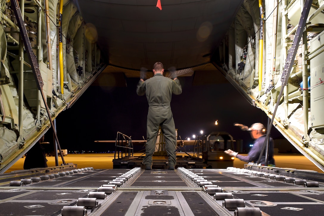 An airman marshals a Tunner 60K loader carrying simulated cargo to off load unto a C-130J Hercules aircraft before a training mission at Dyess Air Force Base, Texas, March 30, 2016. Air Force photo by Senior Airman Keith James