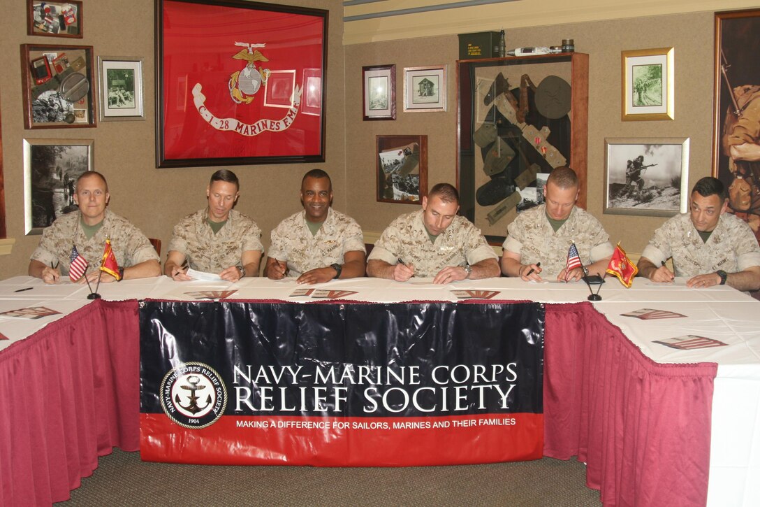 Col. Rollin Brewster, commanding officer of Marine Corps Embassy Security Group; Col. Todd Oneto, commanding officer of Headquarters and Service Battalion; Col. Melvin Carter, commanding officer of Marine Corps Intelligence Activity; Lt. Col. William Pacatte, commanding officer of Marine Corps Air Facility Quantico; Lt. Col. Robert Cato III, commanding officer of Security Battalion; and Col. Joseph Murray, commander of Marine Corps Base Quantico, sign pledges for the 2016 Navy Marine Corps Relief Society fundraising drive.