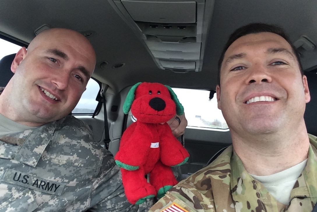 Army Chief Warrant Officer 4 Michael Campbell and Sgt. Michael Miner pose for a photo with a stuffed animal named Dawg in Savannah, Ga., March 9, 2016. Campbell found the stuffed animal in a hotel room near Fort Polk, La., located its 10-year-old owner and sent Dawg back to the boy with a certificate and medal. Courtesy photo by Chief Warrant Officer 4 Michael Campbell