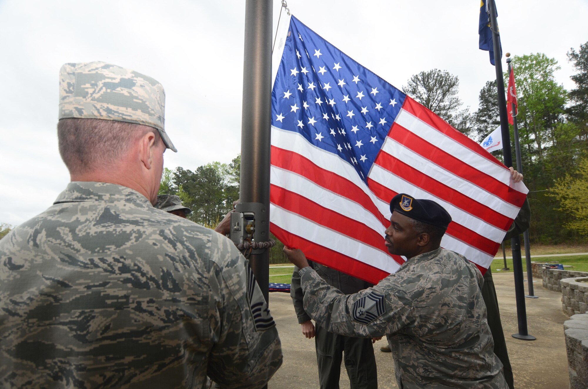 Chief Master Sgt. Jesse Frison joins other Dobbins Chiefs’ Group members in raising an American flag at POW-MIA Memorial Park, Dobbins Air Reserve Base, Georgia, March 31, 2016. With help from the Dobbins Thrift Store staff, the group raised seven new replacement flags at the memorial. (U.S. Air Force photo/ Don Peek)