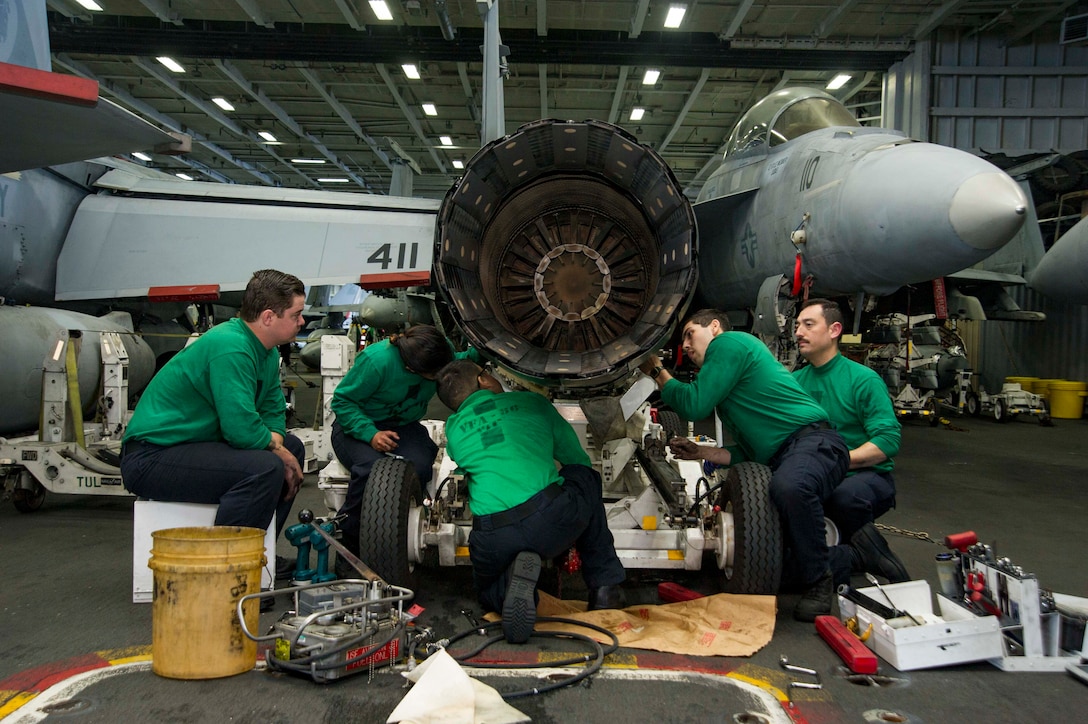 Sailors perform maintenance on a jet engine in the hangar bay of the aircraft carrier USS Dwight D. Eisenhower in the Atlantic ocean, April 6, 2016. The Eisenhower is conducting unit training exercises for future deployment. Navy photo by Seaman Casey S. Trietsch