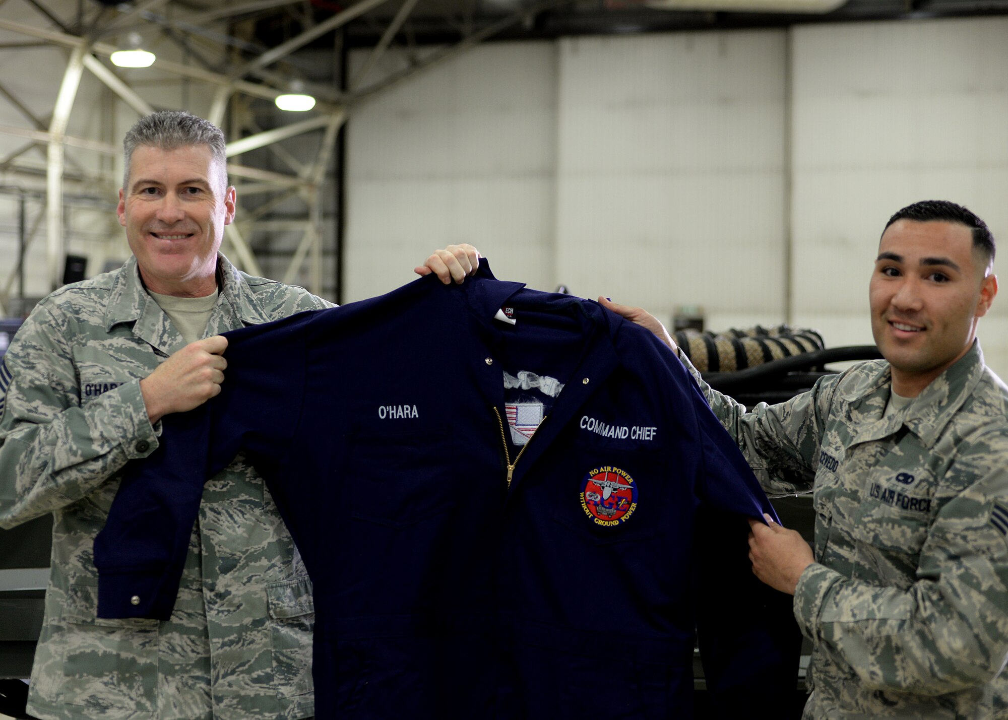 Chief Master Sergeant David O’Hara, Command Chief Master Sergeant for the 48th Fighter Wing holds up a set of custom coveralls, presented to him by Senior Airman Kevin Acevedo Nuñez, 48th Equipment Maintenance Squadron, Aerospace Ground Equipment Maintenance section journeyman, March 30, 2016, at Royal Air Force Lakenheath, England. During his visit, O’Hara worked side-by-side with AGE Airmen and received an in-depth rundown of the unit’s operations and processes. (U.S. Air Force photo/ Technical Sgt. Matthew Plew)