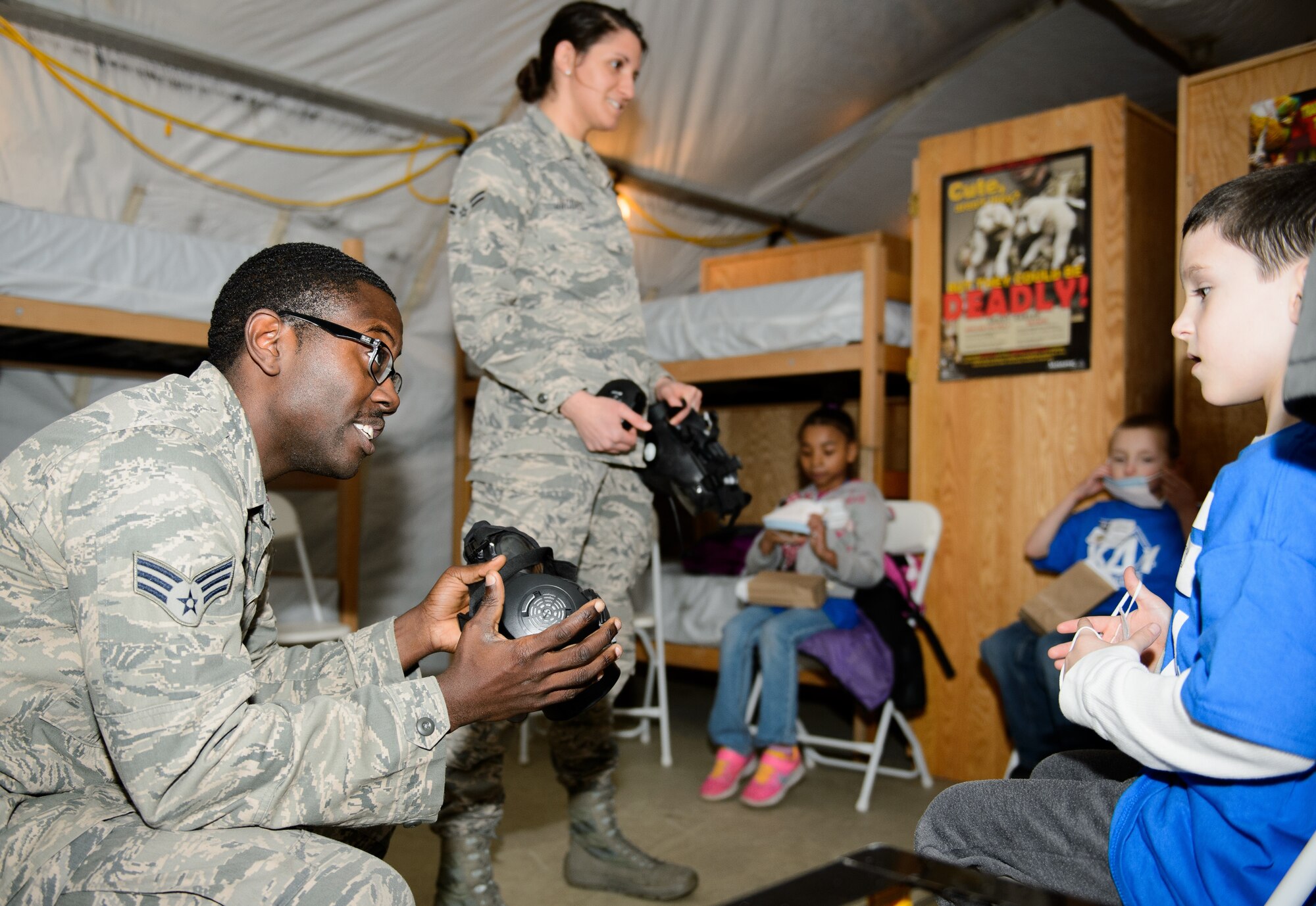 Senior Airman Michael Blocker and Airman 1st Class Brandi Jacobs, both 86th Aerospace Medical Squadron public health technicians, show children gas masks at Ramstein Air Base, Germany, April 1, 2016. The 435th Construction and Training Squadron joined forces with many base squadrons to showcase some of the aspects of a deployment. (U.S. Air Force photo/Staff Sgt. Armando A. Schwier-Morales)