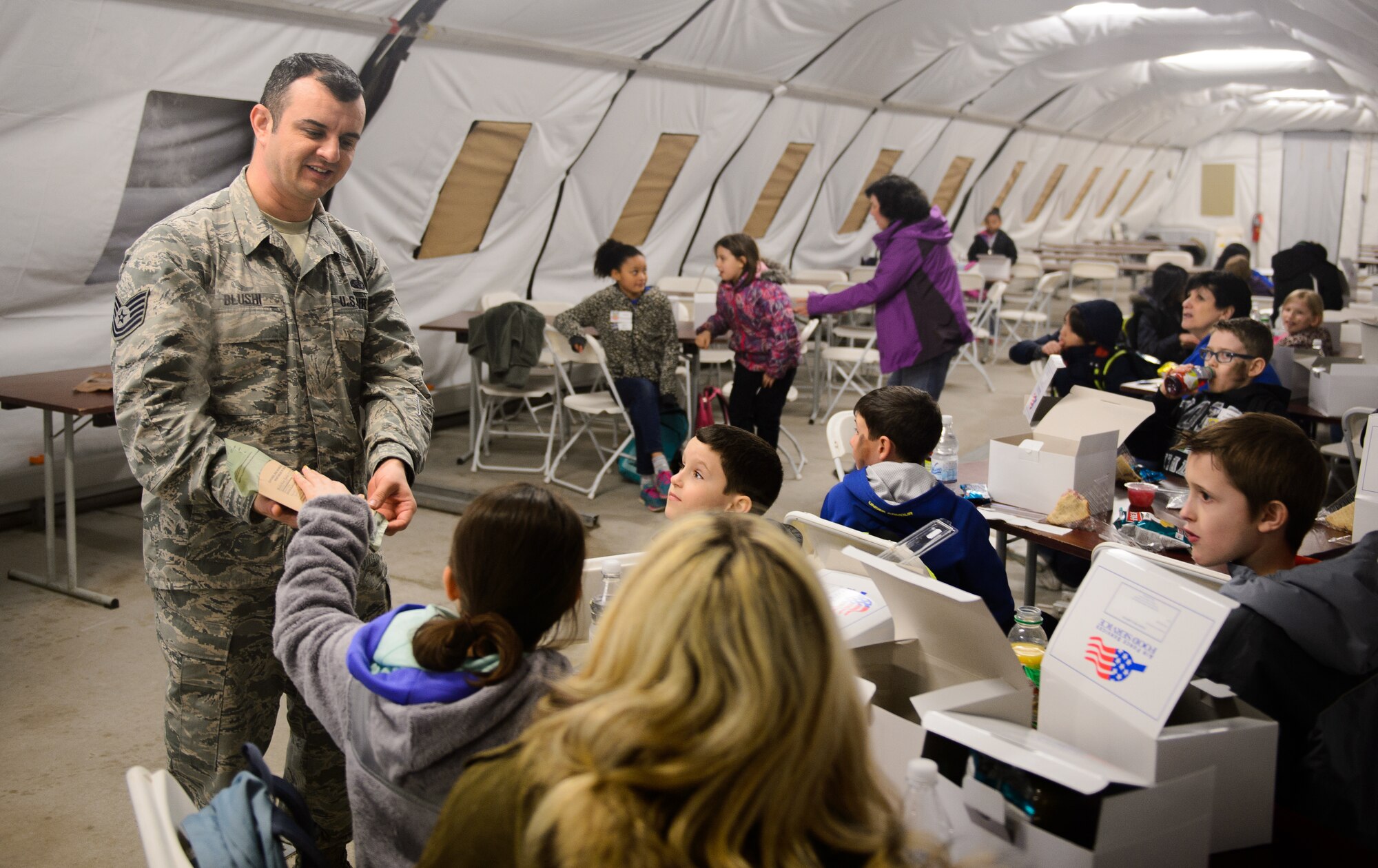 Tech. Sgt. Gencian Blushi, 435th Construction and Training Squadron forces support NCO in charge, shows children a meal ready to eat during their deployments at Ramstein Air Base, Germany, April 1, 2016. Ramstein hosted a mock deployment for children at the Intermediate School. (U.S. Air Force photo/Staff Sgt. Armando A. Schwier-Morales)