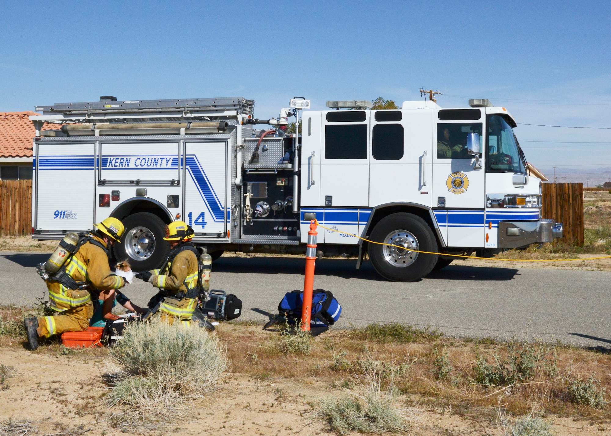As Bakersfield fire fighters treat a wounded civilian, a Kern County Fire Department engine arrives. Edwards Air Force Base partnered with three different fire departments in the local area April 4 during Exercise Desert Wind 16-02. The emergency response exercise took place in California City. (U.S. Air Force photo by Kenji Thuloweit)