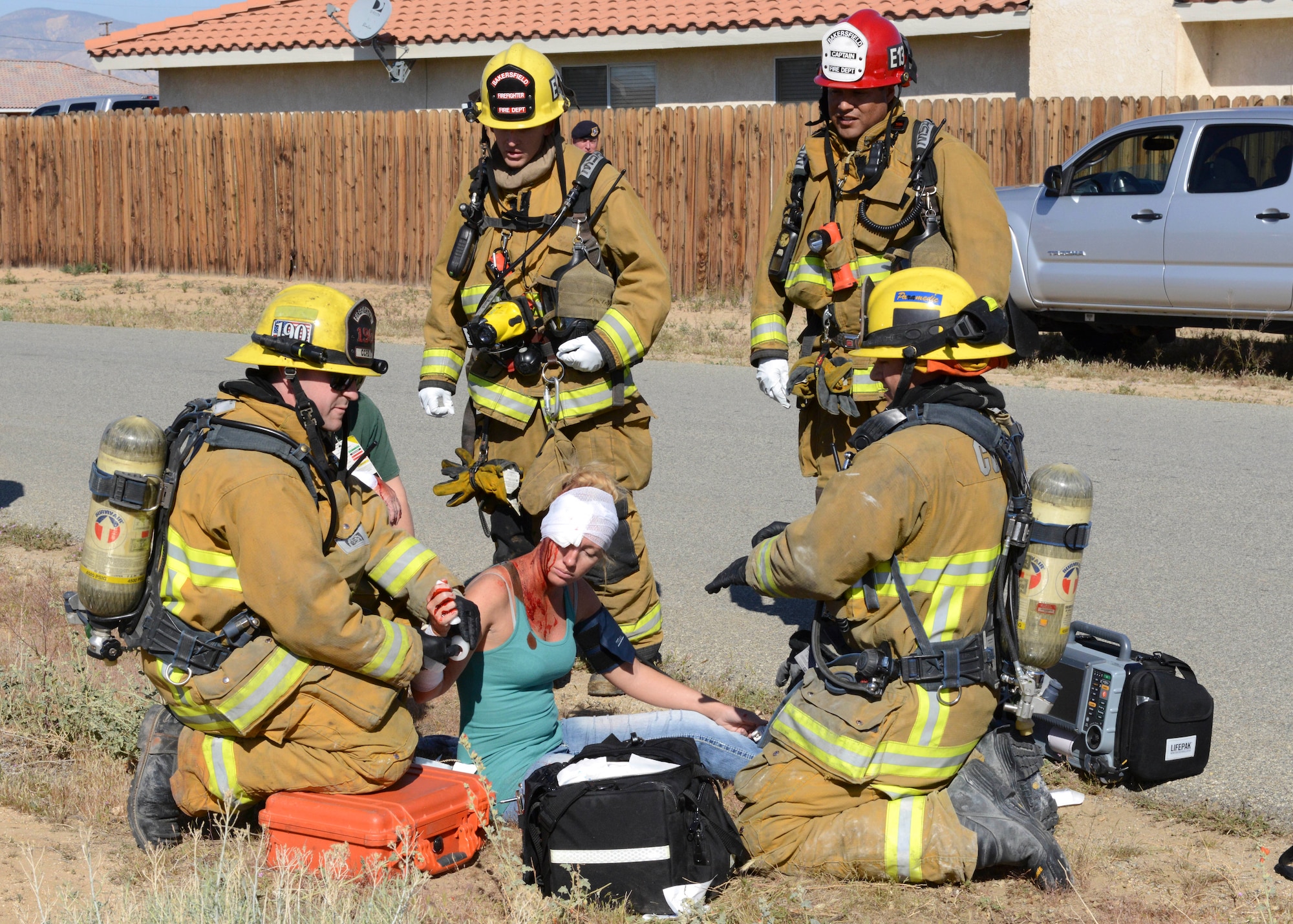 Fire fighters treat a wounded civilian April 4 during Exercise Desert Wind 16-02. To make the exercise as realistic as possible, fake wounds were applied to volunteers and fire and aircraft parts were set at the crash scene. The scenario was a Royal Air Force F-35 crash in the middle of California City. (U.S. Air Force photo by Kenji Thuloweit)