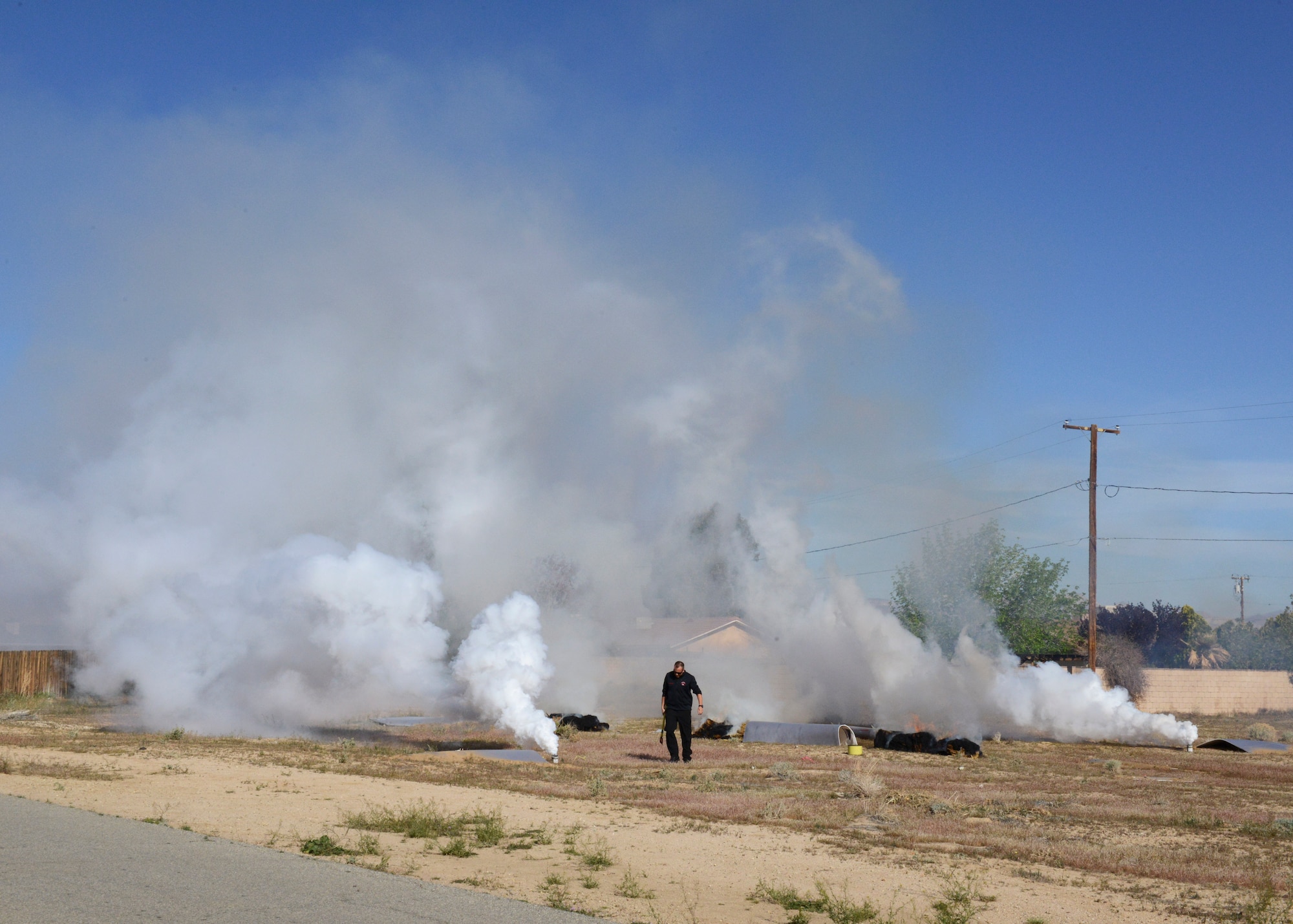 A California City firefighter makes his way to safety after stoking some flames to simulate an aircraft crash site April 4 in California City, California. The scene was part of a joint training exercise between Edwards Air Force Base and fire departments from Cal City, Bakersfield and Kern County. (U.S. Air Force photo by Kenji Thuloweit)