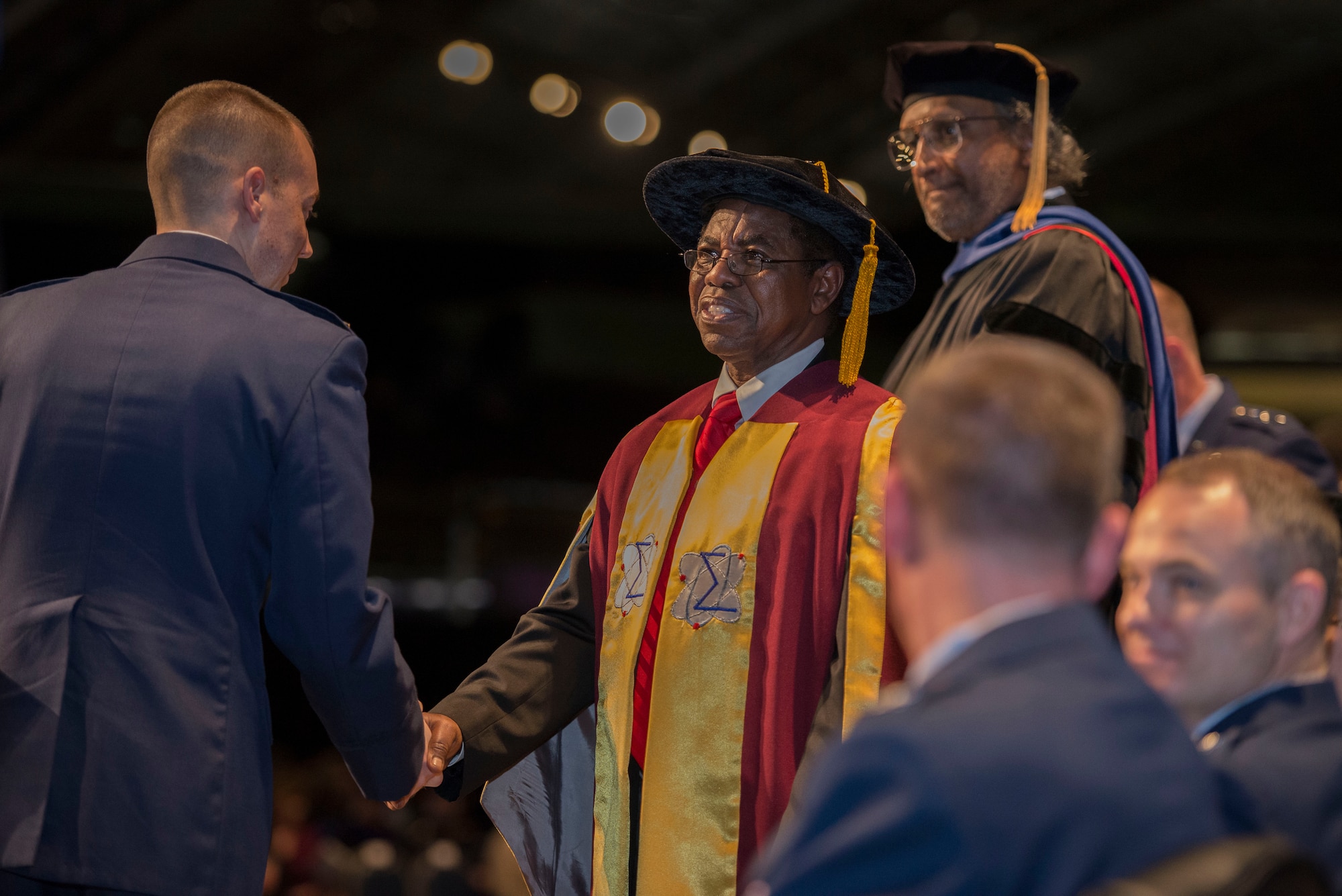 Dr. Adedeji B. Badiru, Dean, Graduate of Engineering and Management at the Air Force Institute of Technology congratulates a graduate during the Air Force Institute of Technology Commencement Ceremony March 24, 2016 at the National Museum of United States Air Force. AFIT represents a collection of like-minded scholars, students, researchers, and administrators dedicated to sustaining the intellectual superiority of the defense programs of the United States.  (U.S. Air Force photo by Michelle Gigante) 