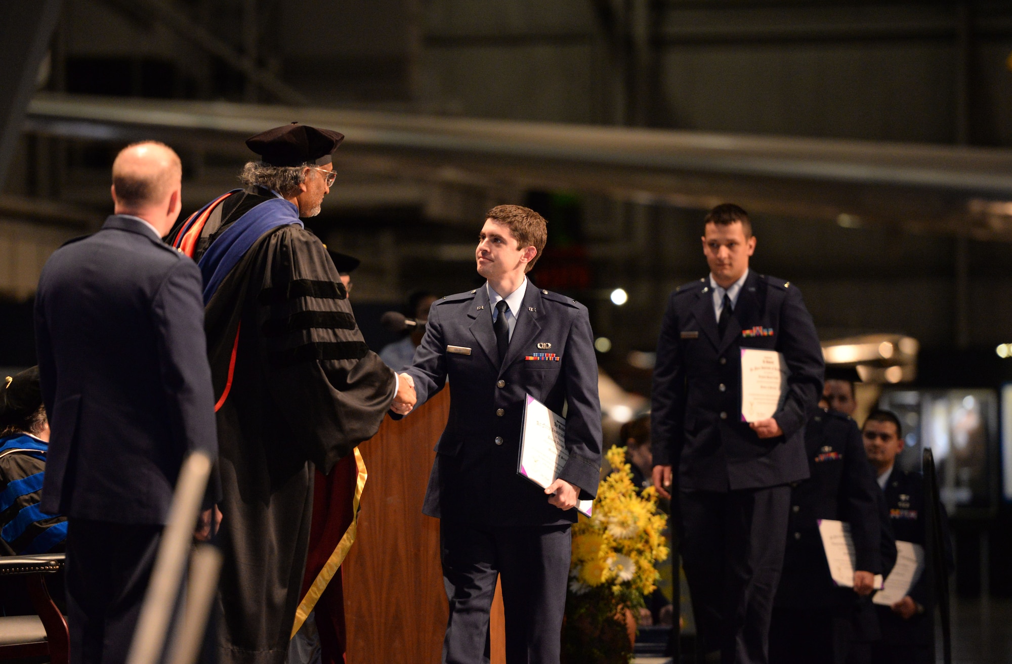Graduates line up to receive their diplomas during the Air Force Institute of Technology Commencement Ceremony March 24, 2016 at the National Museum of United States Air Force. AFIT is committed to graduate instructional and research programs in science technology, engineering, and mathematics areas. (U.S. Air Force photo by Michelle Gigante)