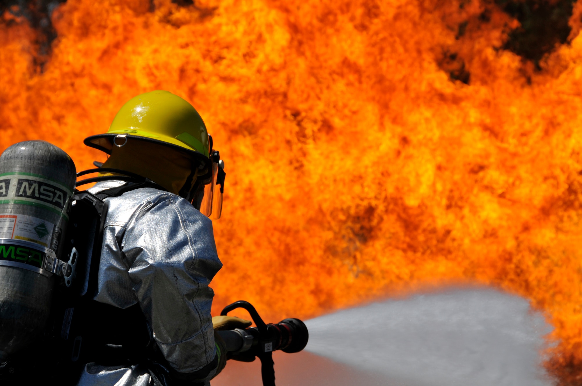 A picture of Airmen from Connecticut, Maine, New Jersey, Rhode Island and Vermont Air National Guard Fire Departments performing a live aircraft fire training exercise.