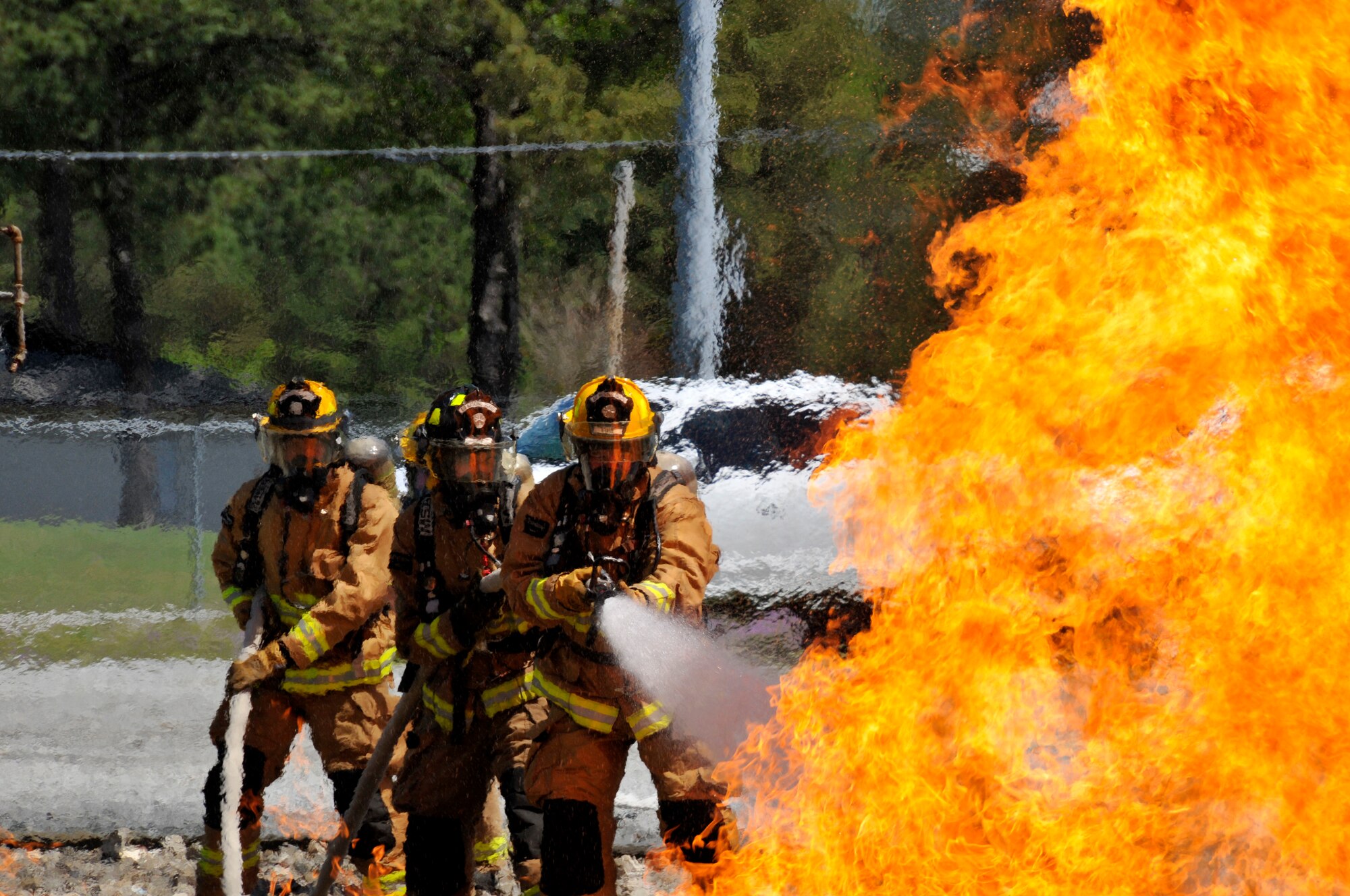 A picture of Airmen from the Connecticut, Maine, New Jersey, Rhode Island and Vermont Air National Guard Fire Departments performing a live aircraft fire training exercise.