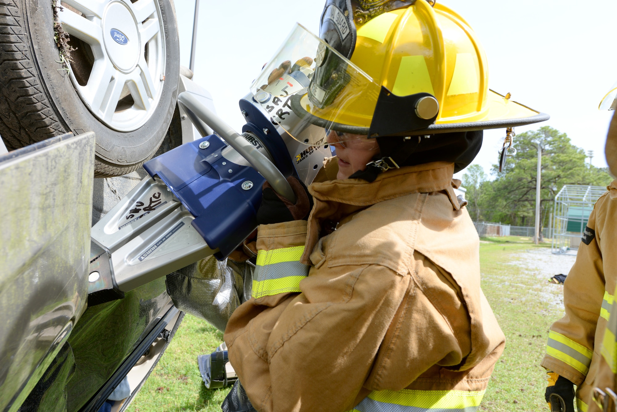 A picture of Senior Airman Katelyn Mosley of the 101st Airlift Wing Fire Department, Maine Air National Guard, utilizing a Hurst spreader to open a vehicle door.