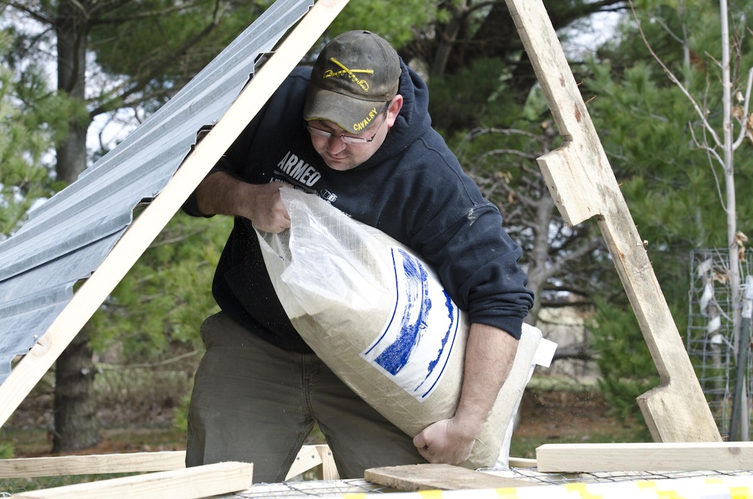 Joe Villines, an Army Sgt. with the U.S. Army Reserve pours a bag of organic chicken feed into a newly constructed chicken pen on his farm in Cummings, Iowa, March 18, 2016. Villines manages to find the balance between his military obligations, his civilian career with the Department of Veterans Affairs, fatherhood, and a growing passion in rural farming. Joe is increasing his knowledge on traditional farming and becoming a man of the soil, and in the process giving back to his local community.(U.S. Army Reserve photo by  Brian Godette, USARC Public Affairs)