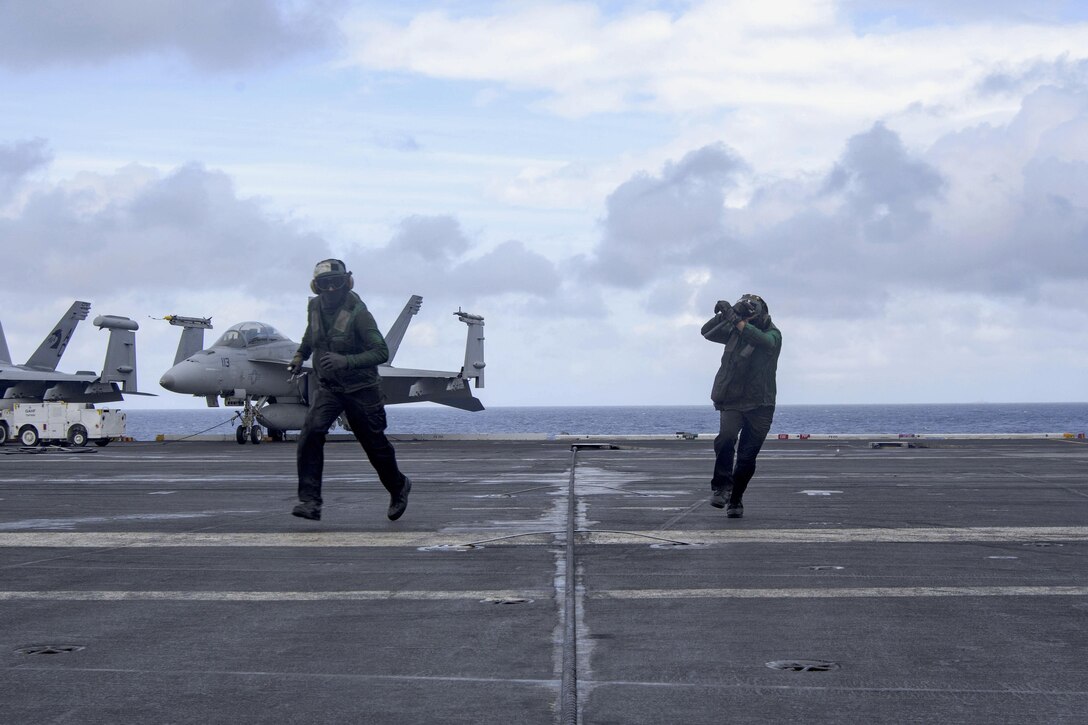Navy Seamen Tyler Jones, left, and Eugene Lucila clear the landing area after inspecting an arresting gear wire support on the flight deck of the aircraft carrier USS Dwight D. Eisenhower in the Atlantic Ocean, March 31, 2016. Jones is an aviation boatswain's mate equipment airman and Lucila is an airman. Navy photo by Petty Officer 3rd Class Anderson W. Branch