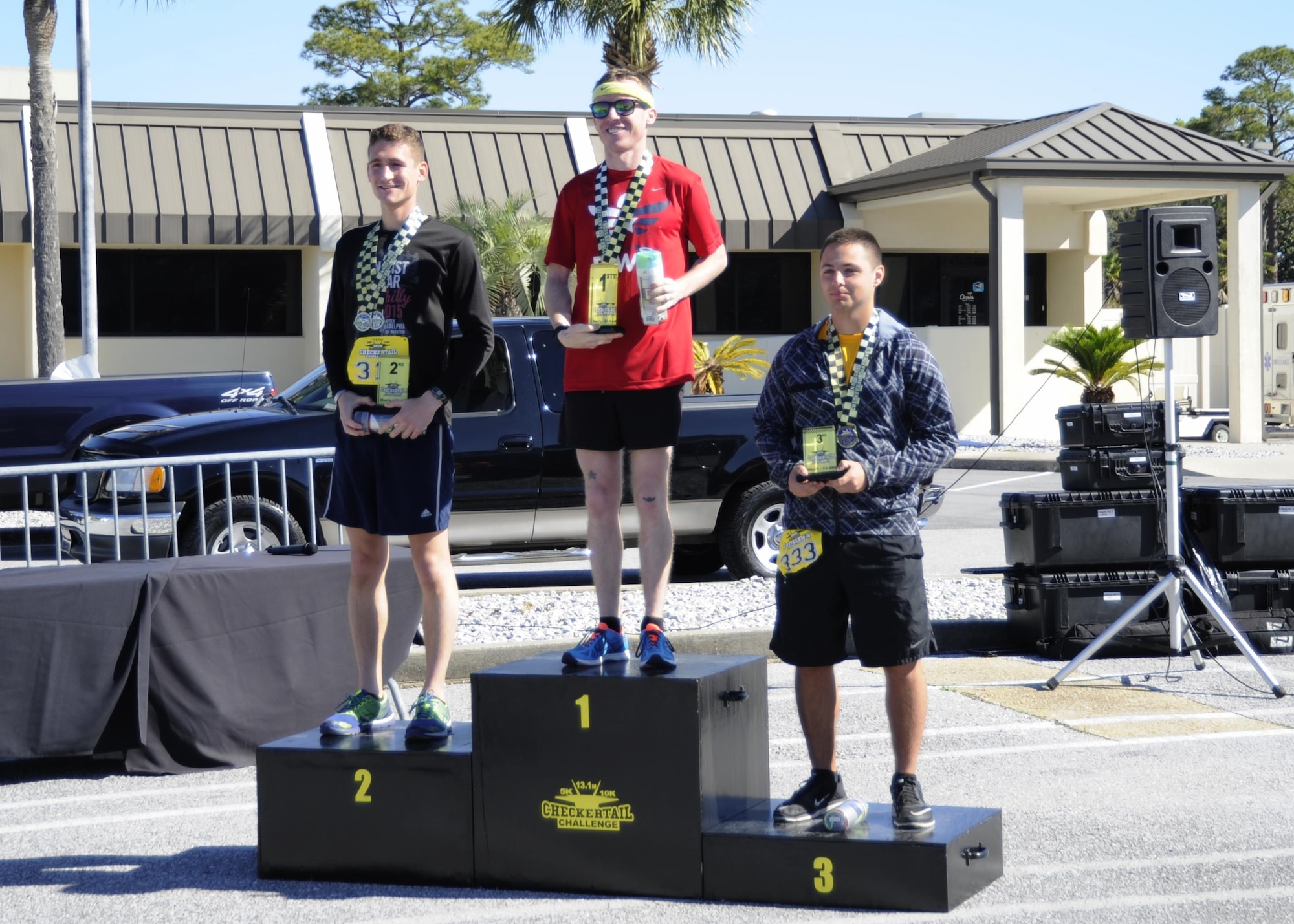(From left to right:) 1st Lt. Myles Tucker, 325 Maintenance Group executive officer,  Tech. Sgt. Blaine Truman, 43rd Aircraft Maintenance Unit F-22 Raptor assistant section chief, and  Airman 1st Class Alex Jenkins, 325 Logistics Readiness Squadron vehicle management and analysis technician, stand on the Checkertail Challenge  winners stand April 3, at the Horizons Club. The purpose of the event was to promote fitness and a healthy lifestyle, while showcasing Tyndall as a premier location for these types of events. (U.S.  Air Force photo by Senior Airman Solomon Cook/Released)