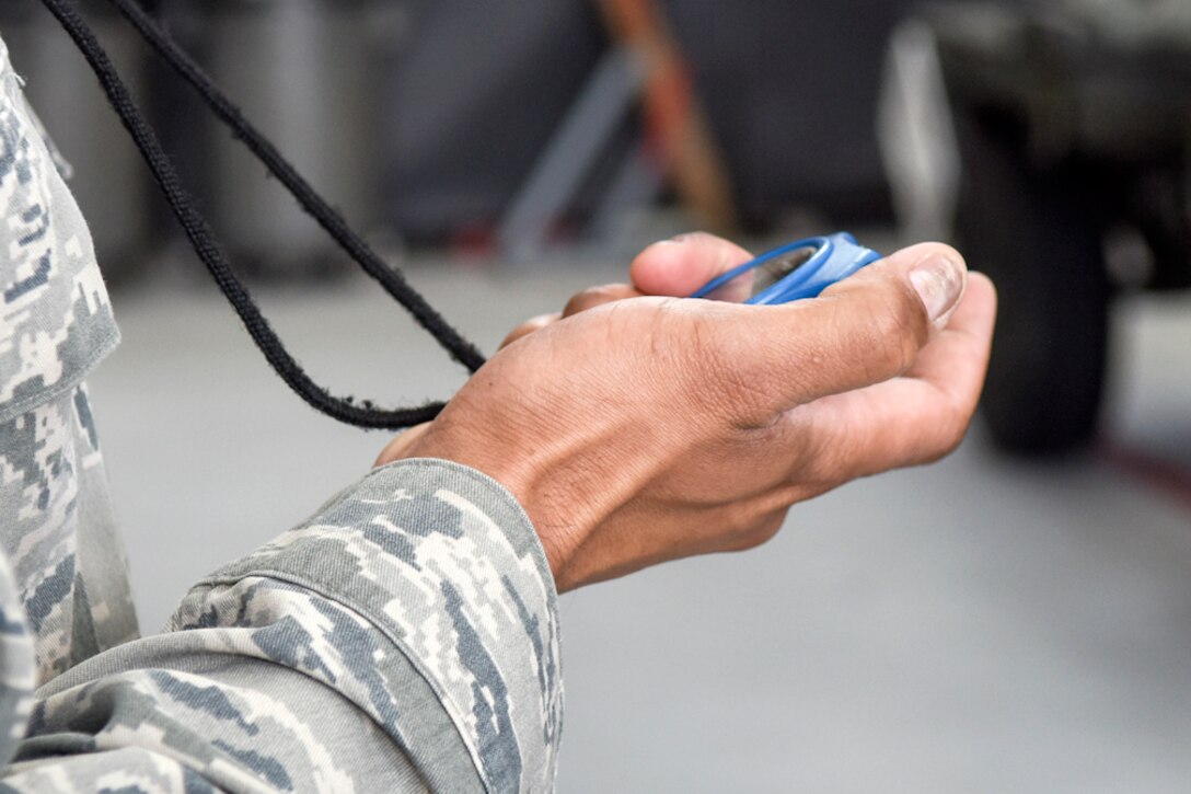 Master Sgt. Jason Rosalis, 4th Maintenance Group load crew of the quarter event coordinator, prepares to stop the timer on a crew competing in a Load Crew of the Quarter competition, April 7, 2016, at Seymour Johnson Air Force Base, North Carolina. Weapon load crews from each of the Aircraft Maintenance Units compete for best time while ensuring accuracy, serviceability and efficiency. (U.S. Air Force photo/Airman Shawna L. Keyes)