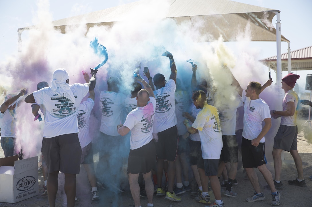 Participants of the Sexual Assault Prevention and Response annual Colorful Consent 5k Run throw colored powder during a ‘color party’ held at the finish line of the run held aboard the Combat Center, April 1, 2016. (Official Marine Corps photo by Cpl. Thomas Mudd/Released)