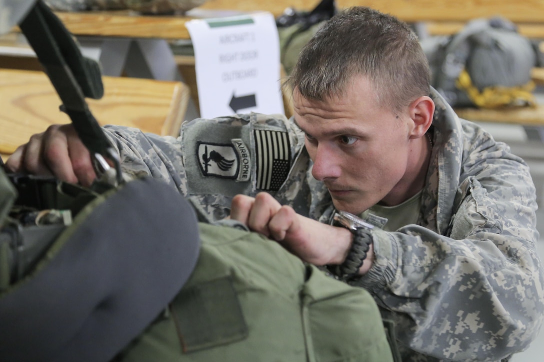 Army Sgt. 1st Class Stephen Ledbetter checks that his fellow paratroopers chute and gear is properly outfitted while preparing for a night jump at the Joint Mobility Complex, Joint Base Elmendorf-Richardson, Alaska, March 31, 2016. Ledbetter is a jumpmaster assigned to the 3rd Battalion, 509th Infantry Regiment. Air Force photo by Alejandro Pena