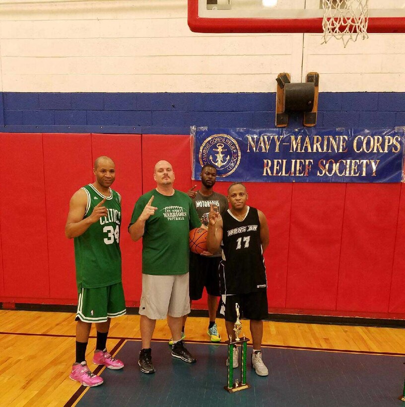 Maj. Lee Taylor (right), and teammates (left to right) Gunnery Sgt. Jerome McCray, Stewart Snoddy and Tennoris Knox walk away with the 1st place trophy in a 3-on-3 basketball tournament at Marine Corps Logistics Base Albany’s Thomason Gym, recently. “We went undefeated throughout the tournament and played a total of four games,” Taylor said on his team’s championship win. Eight teams participated in the event, which was one of three activities held on the installation to raise money during the Navy-Marine Corps Relief Society’s Fund Drive.