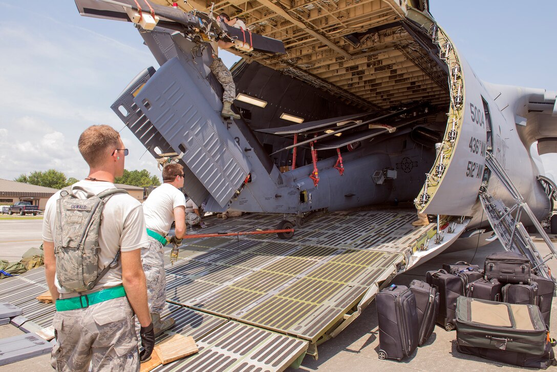 U.S. Air Force Airmen from the 723d Aircraft Maintenance Squadron load an HH-60G Pave Hawk onto a HC-130J Combat King II outside of the Deployment Control Center prior to deploying, July 16, 2015, at Moody Air Force Base, Ga. The DCC prepares, evaluates and supervises all logistical operations to determine deployment tasking for Moody’s personnel. (U.S. Air Force photo by Airman 1st Class Greg Nash/Released) 
