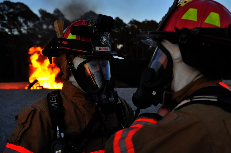 Douglas Woods, a firefighter with the 1st Special Operations Civil Engineer Squadron, watches an Airman gear up before a firefighting exercise at Hurlburt Field, Fla., April 4, 2016. During the exercise firefighters tested their proficiency on extinguishing exterior and interior fires on a simulated C-130 aircraft. (U.S. Air Force photo by Airman 1st Class Joseph Pick)