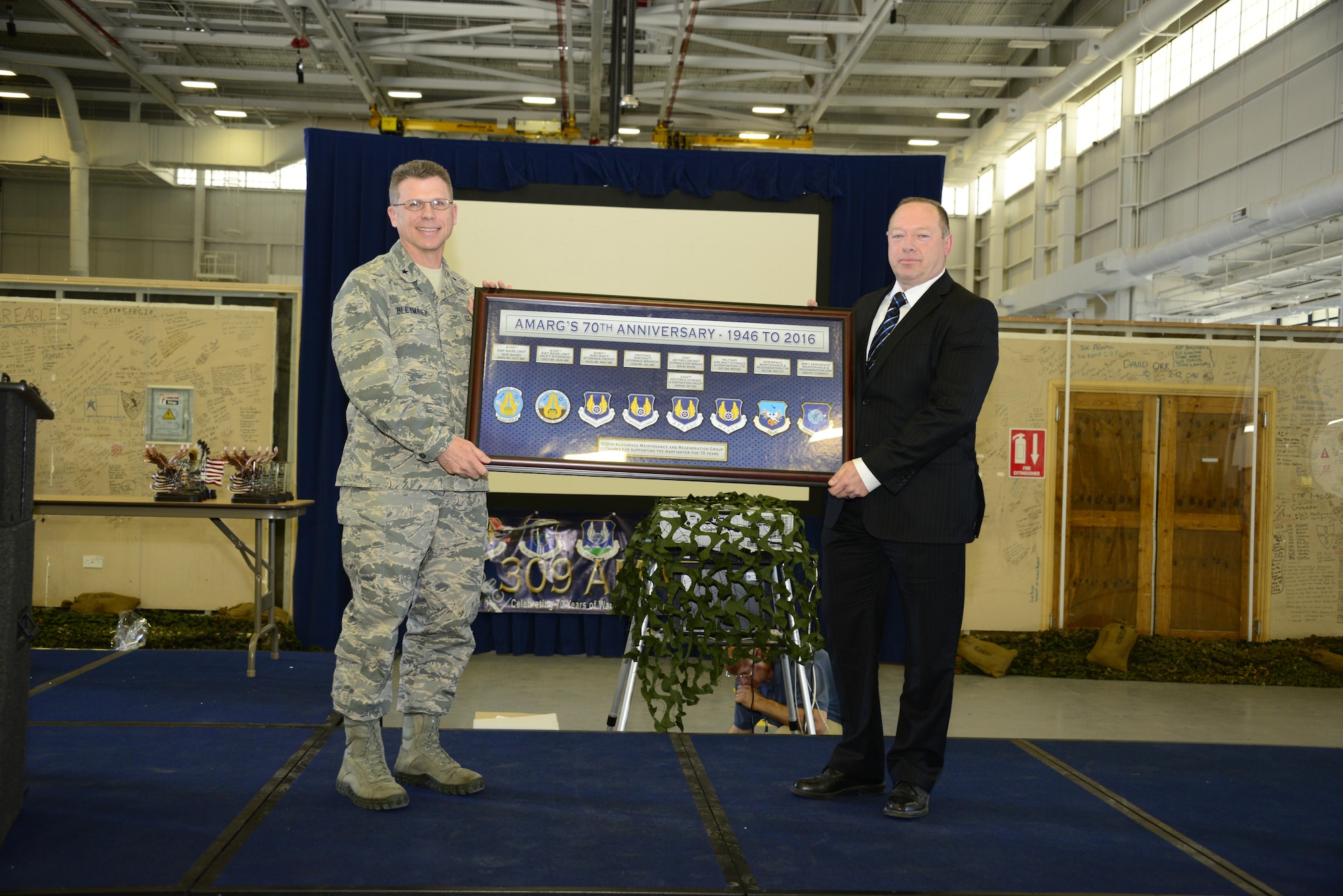 U.S. Air Force Brig. Gen. Steven J. Bleymaier, Commander of Ogden Air Logistics Complex at Hill Air Force Base, Utah, presents a commemorative plaque to Tim Gray, 309th Aerospace Maintenance and Regeneration Group deputy director, during the 70th Anniversary Celebration of the 309th AMARG at Davis-Monthan Air Force Base, Ariz., April 4, 2016.  Although the name has changed over the years the organization has continued achieving its mission elements: aircraft storage and preservation, reclaiming and returning vital parts into the supply chain, regenerating valuable aircraft to flying service and providing limited depot maintenance and modifications.  (U.S. Air Force Photo by Senior Airman Chris Massey/Released)