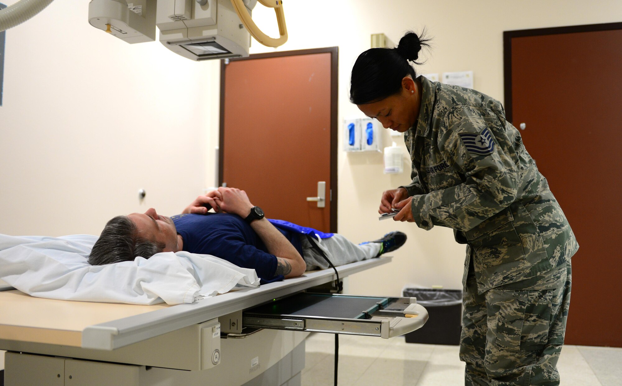 U.S Air Force Tech. Sgt. Mia Newmeyer, the 354th Medical Group Diagnostics and Therapeutics flight chief, inserts a marker and a cassette into a cassette tray, April 6, 2016, at Eielson Air Force Base, Alaska. The marker tells doctors reading the x-ray what side of the body they are looking at on the cassette. (U.S. Air Force photo by Airman 1st Class Cassandra Whitman/Released)