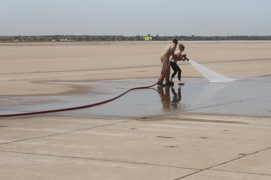 A Marine with Aircraft Rescue and Firefighting aboard Marine Corps Air Station Miramar assists an educator with using a fire hose during an Educators Workshop aboard MCAS Miramar, Calif., April 6. Educators from recruiting stations Lansing, Mich., and Twin Cities, Minn., visited MCAS Miramar to learn about the aviation side of the Marine Corps and life for a Marine after basic training