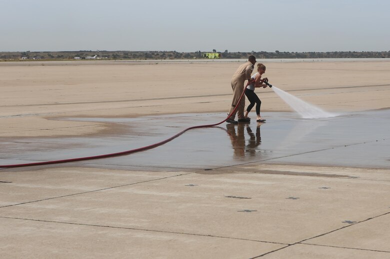 A Marine with Aircraft Rescue and Firefighting aboard Marine Corps Air Station Miramar assists an educator with using a fire hose during an Educators Workshop aboard MCAS Miramar, Calif., April 6. Educators from recruiting stations Lansing, Mich., and Twin Cities, Minn., visited MCAS Miramar to learn about the aviation side of the Marine Corps and life for a Marine after basic training