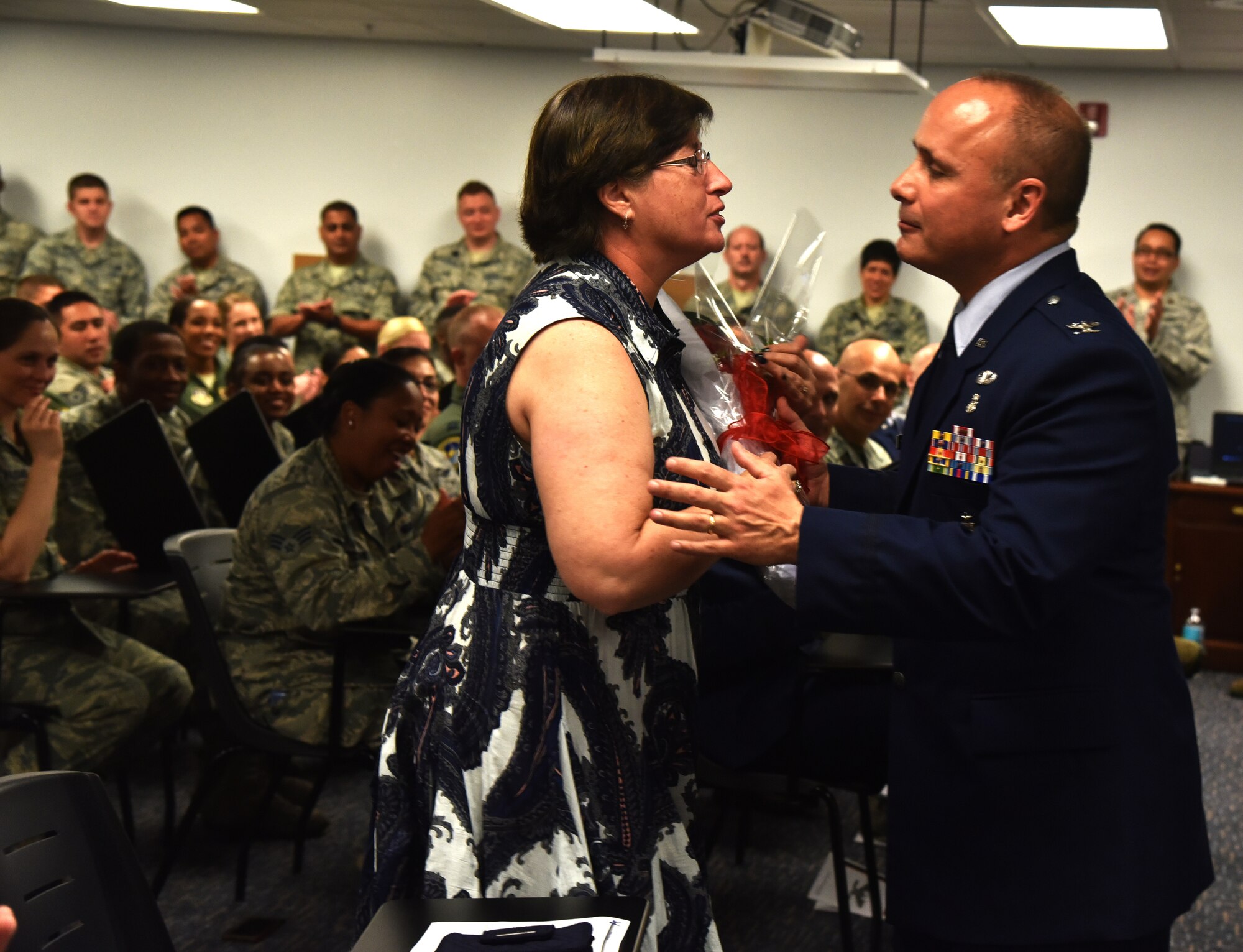 Members of the 45th Aermedical Evacuation Squadron celebrate as Col. James Palmisano presents his wife with flowers following his promotion ceremony to the rank of Colonel. Palmisano expressed how his promotion would not have been possible without the love, dedication and support from his beautiful wife. (U.S. Air Force photo by Staff Sgt. Adam C. Borgman)
