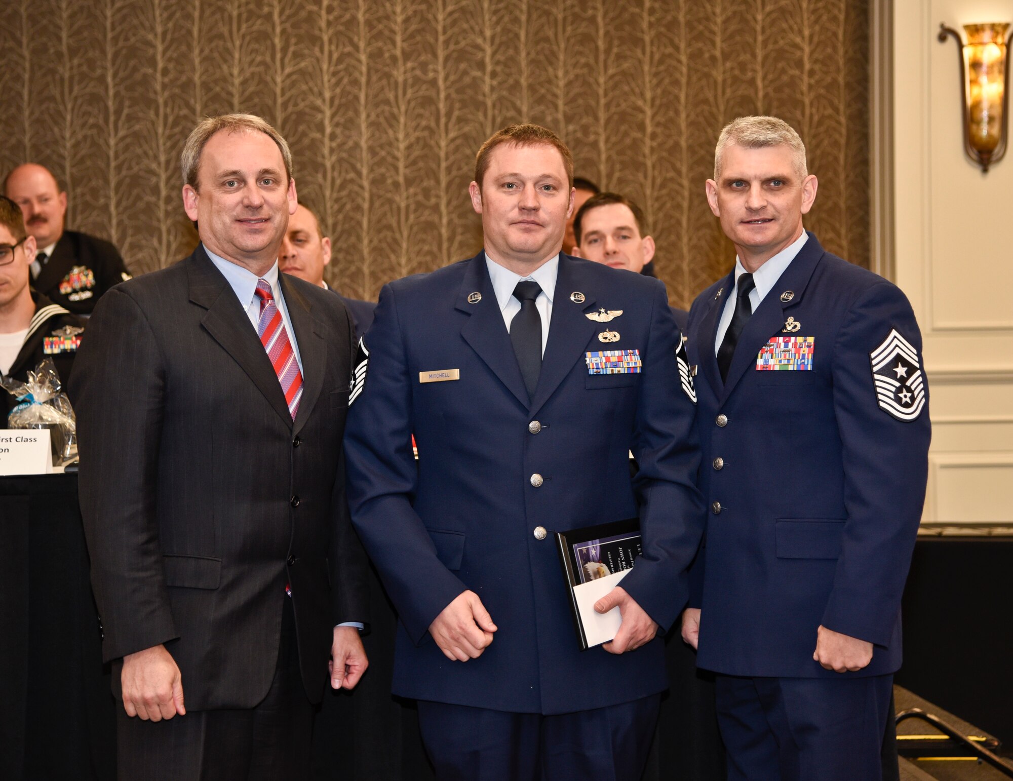 Master Sgt. John Mitchell, 116th Air Refeuling Squadron boom operator instructor, receives the 2016 Armed Forces Persons of the Year award, category Guard/Reserve E-7 through E-9, from Todd Mielke, Greater Spokane Incorporated CEO, and Chief Master Sgt. Christian Pugh, 92nd ARW command chief, during the 60th annual Let Freedom Ring breakfast April 8, 2016, at the Red Lion Hotel at the Park in Spokane, Wash. The event honored military members from all branches, and recognized the Armed Forces Persons of the Year.