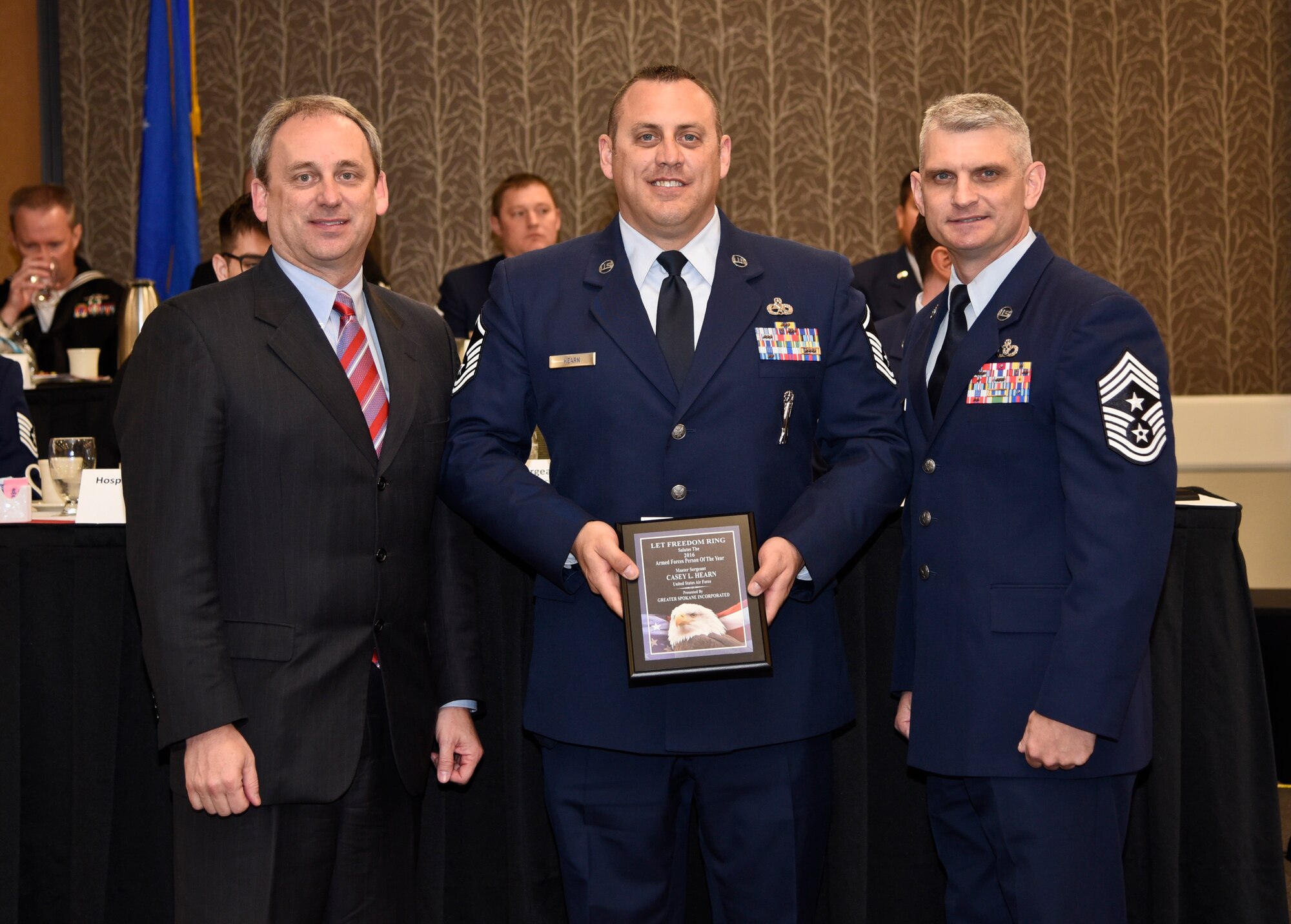 Master Sgt. Casey Hearn, 92nd Maintenance Squadron NCO in charge of munitions accountability, receives the 2016 Armed Forces Persons of the Year award, category E-7 through E-9, from Todd Mielke, Greater Spokane Incorporated CEO, and Chief Master Sgt. Christian Pugh, 92nd ARW command chief, during the 60th annual Let Freedom Ring breakfast April 8, 2016, at the Red Lion Hotel at the Park in Spokane, Wash. The event honored military members from all branches, including GSI presenting the Armed Forces Persons of the Year award. Hearn competed against two other military members for this award. (U.S. Air Force Photo/Airman 1st Class Taylor Bourgeous)