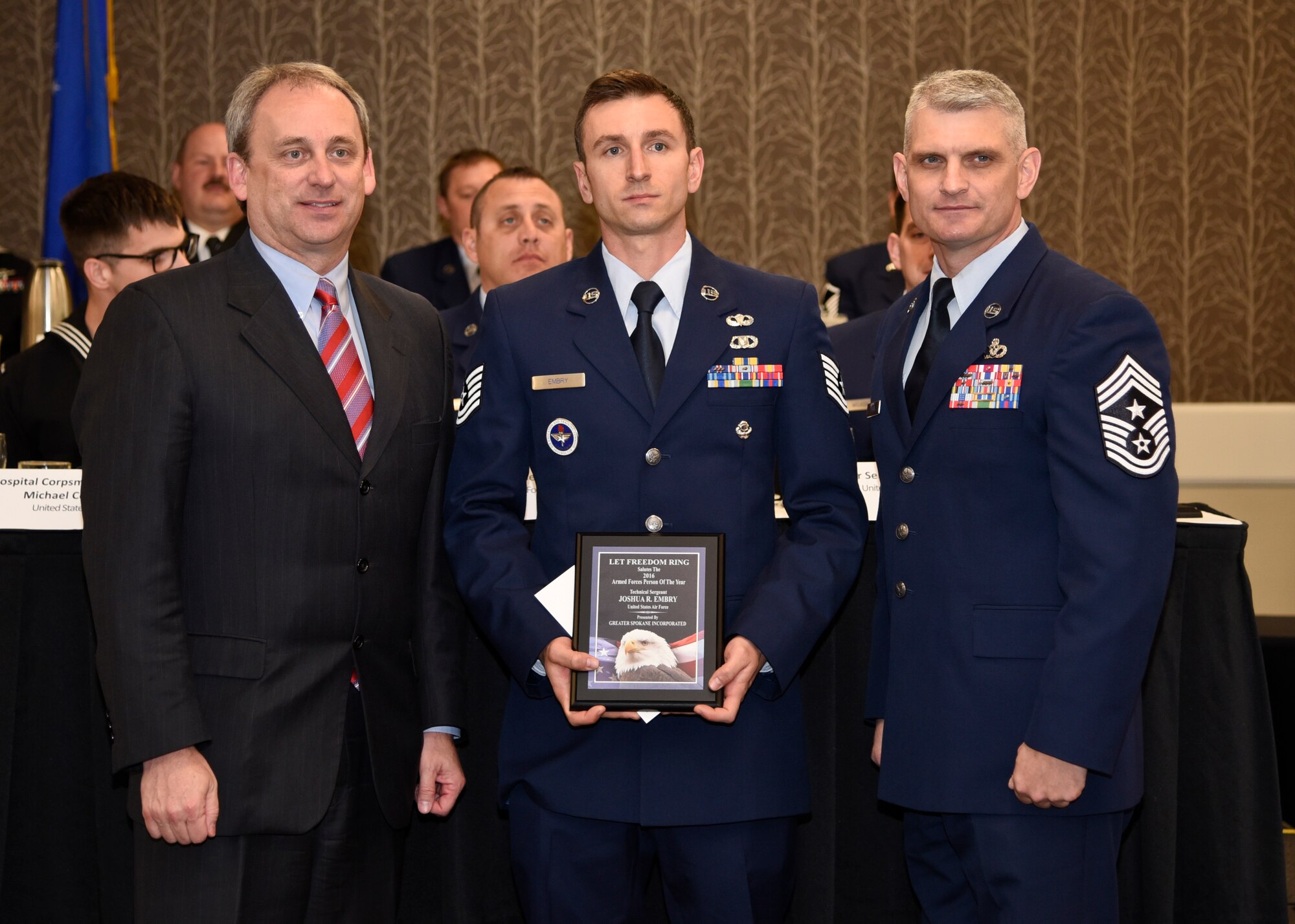 Tech. Sgt. Joshua Embry, 66th Training Squadron Survival, Evasion, Resistance and Escape instructor, receives the 2016 Armed Forces Persons of the Year award, category E-5 through E-6, from Todd Mielke, Greater Spokane Incorporated CEO, and Chief Master Sgt. Christian Pugh, 92nd ARW command chief, during the 60th annual Let Freedom Ring breakfast April 8, 2016 at the Red Lion Hotel at the Park in Spokane, Wash. Let Freedom Ring celebrates the nation’s military through a special awards program that honors local active duty, guard and reserve members of the armed forces. Embry competed against four other Fairchild Air Force Base members for this award. (U.S. Air Force Photo/Airman 1st Class Taylor Bourgeous)